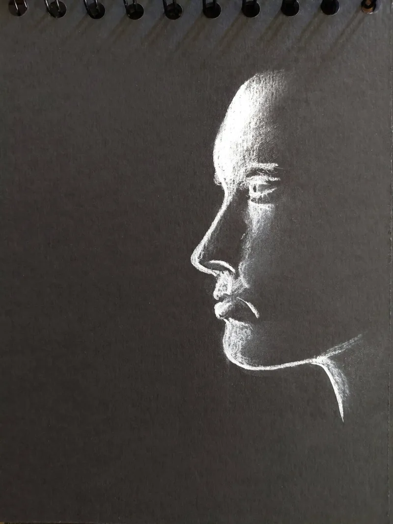 Profil de femme dessiné au pastel blanc sur papier noir : seule la lumière sculpte le visage.