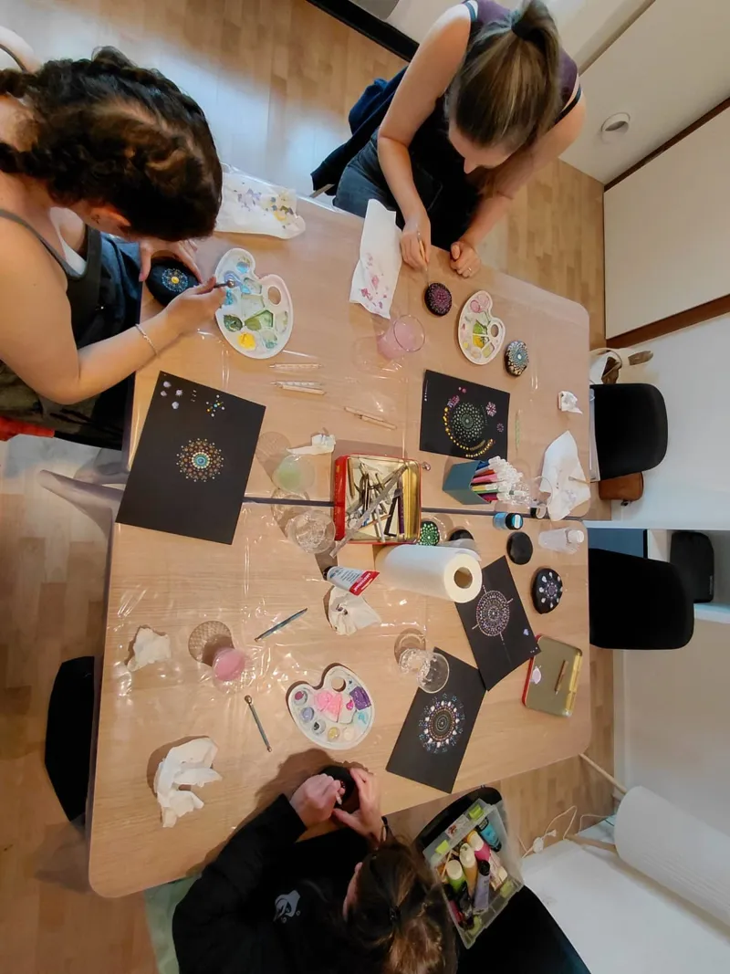 Vue d'ensemble de l'atelier : participants autour d'une table, mandalas en points sur papier noir.