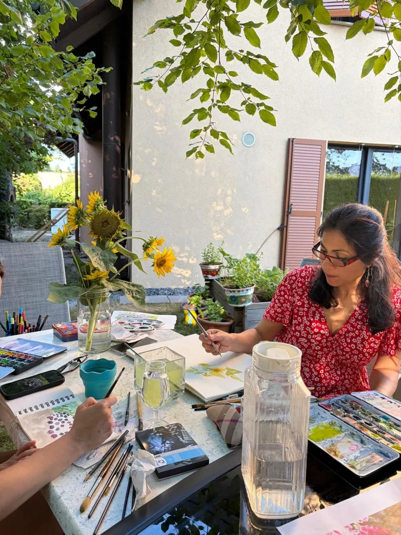 Une participante peint des tournesols à l'aquarelle pendant un cours en plein air.
