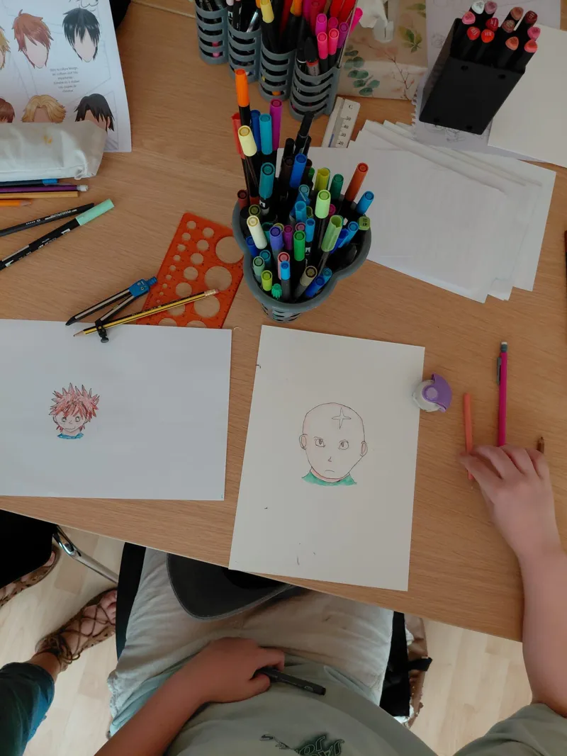 Atelier manga : des enfants dessinent et colorient leurs personnages aux feutres.